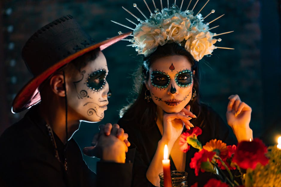 Close-up portrait of a couple in Dia de los Muertos costume and makeup, surrounded by candles.