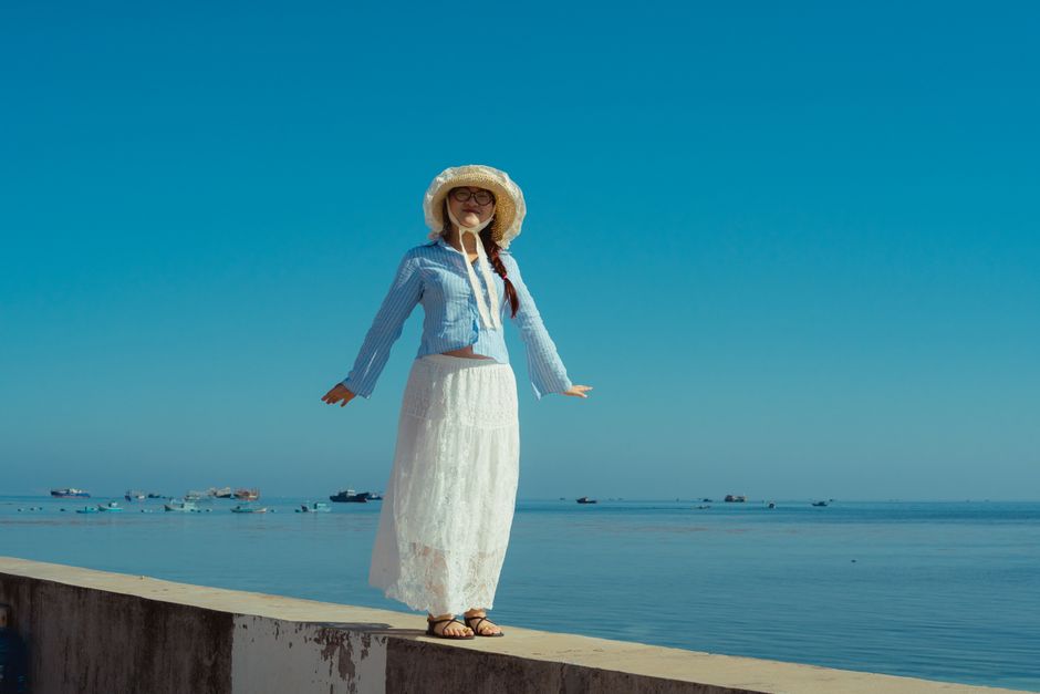 A woman in casual attire enjoys the serene ocean view in Bình Thuận, Vietnam.