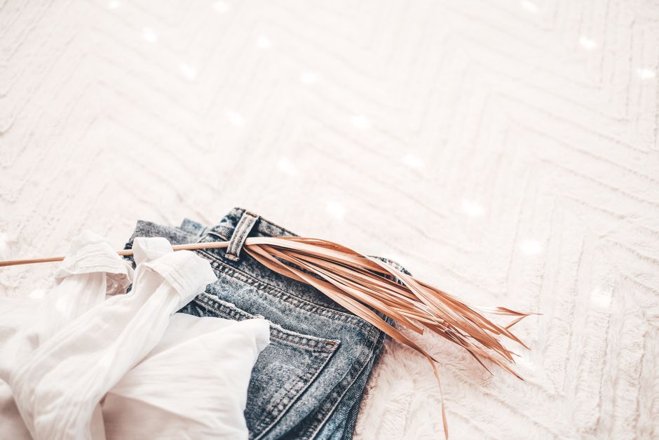 A stylish composition with denim jeans, a white shirt, and dried grass, presenting a minimalist aesthetic.