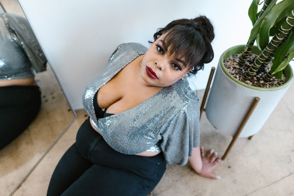 Confident plus-size model posing in a shimmering silver top, embracing body positivity and style.
