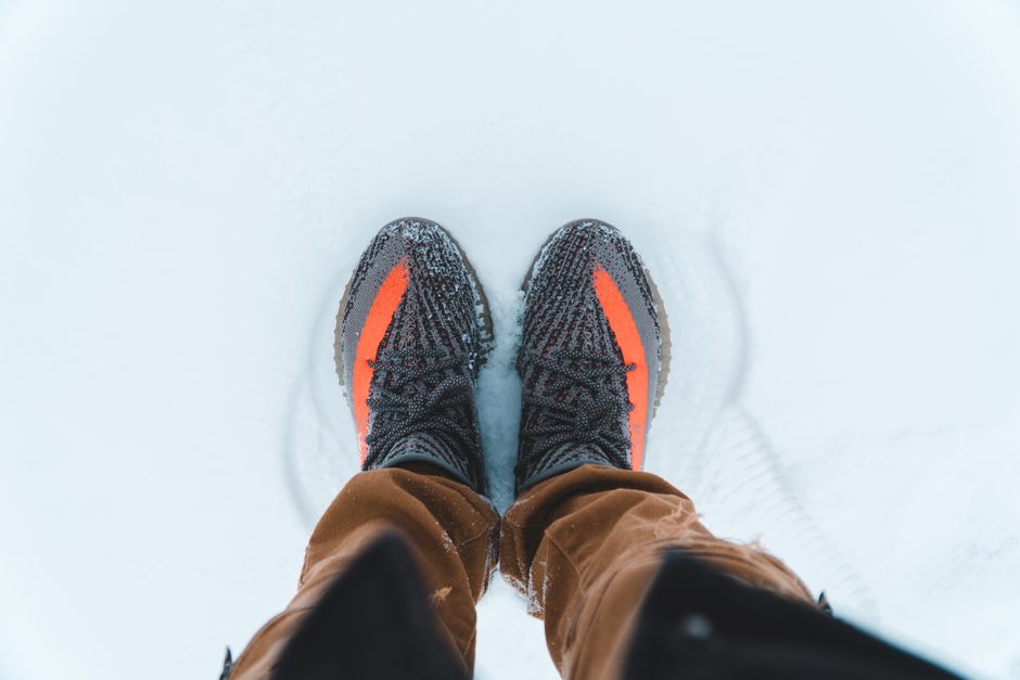 Top view of stylish sneakers on snow, perfect for winter fashion.