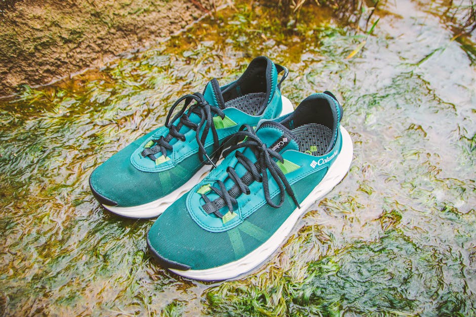 Pair of teal running shoes placed on a mossy wet surface, highlighting outdoor adventure.