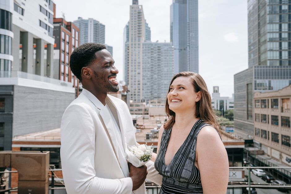Joyful couple sharing a moment on a city rooftop with skyscrapers in the background.