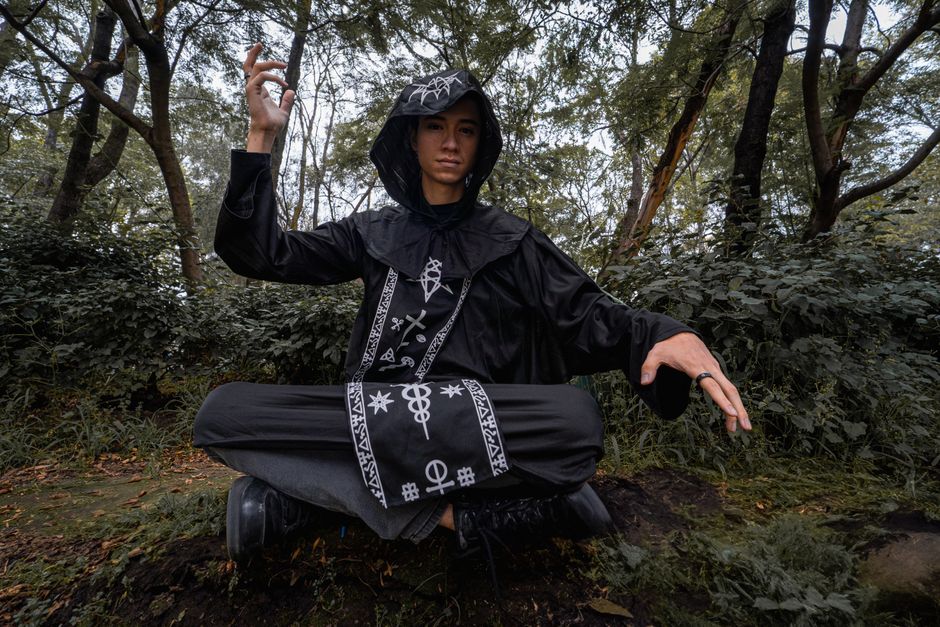 A wizard in a detailed costume practicing levitation in a lush forest.