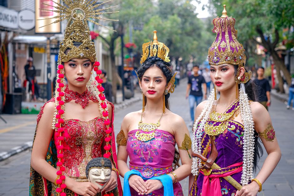 Three women in traditional Indonesian attire participate in a cultural parade on Braga Street, West Java.