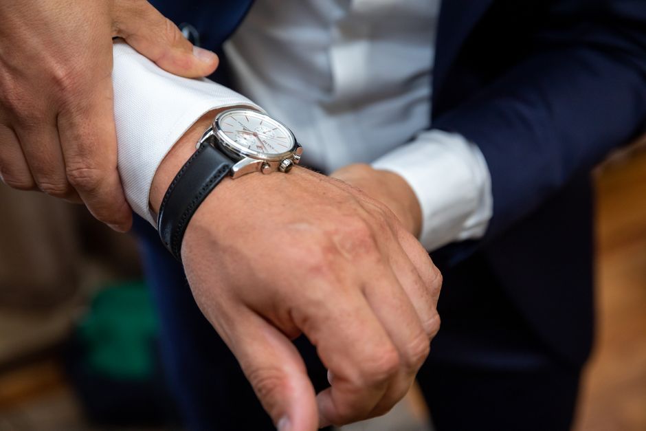 Close-up of a man in a suit adjusting a stylish wristwatch, highlighting elegance.