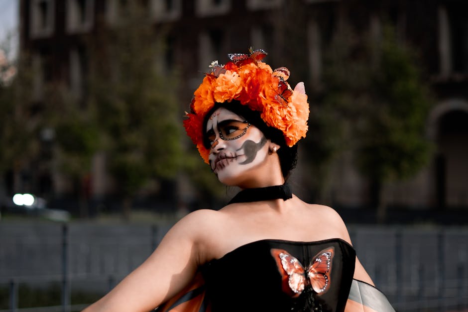 Woman dressed for Day of the Dead in festive makeup and flower crown, adorned with butterflies.