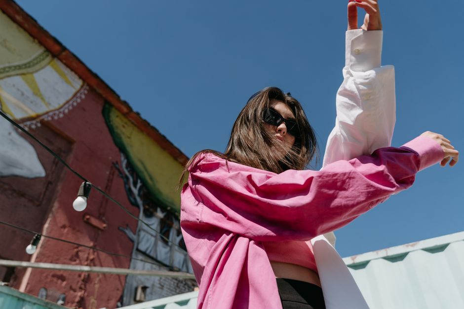 Stylish woman in sunglasses and colorful outfit striking a pose outdoors.