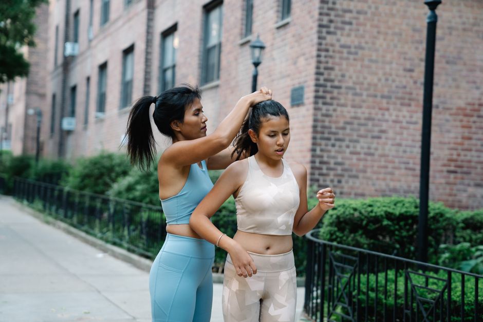 Two women in activewear getting ready for a workout on a city sidewalk.