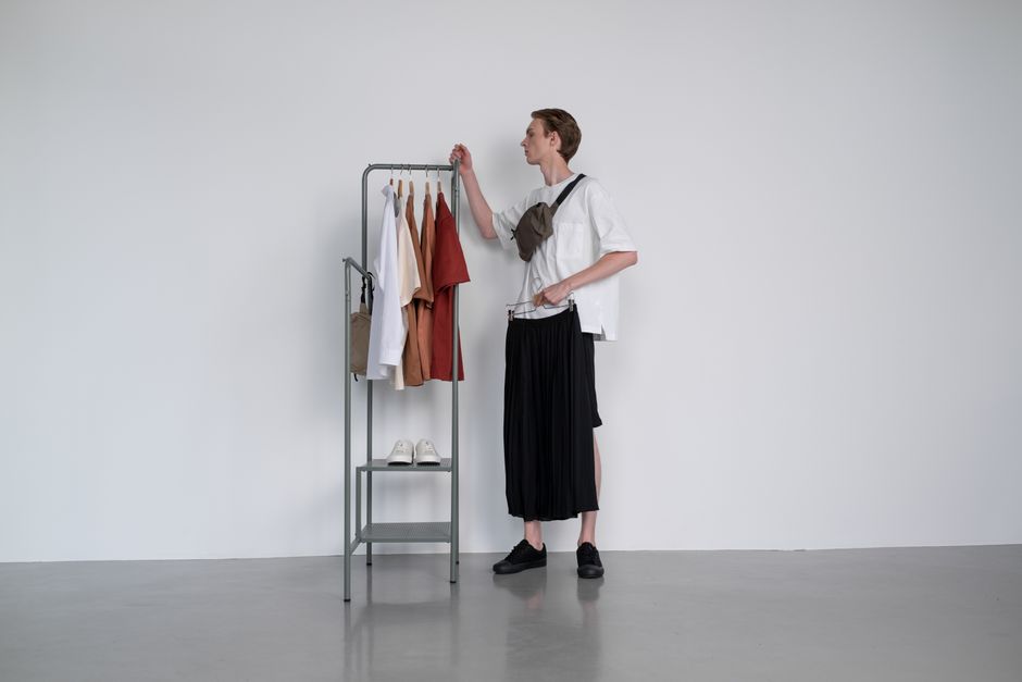 A man examines a clothing rack in a minimalist studio setting, showcasing modern fashion.
