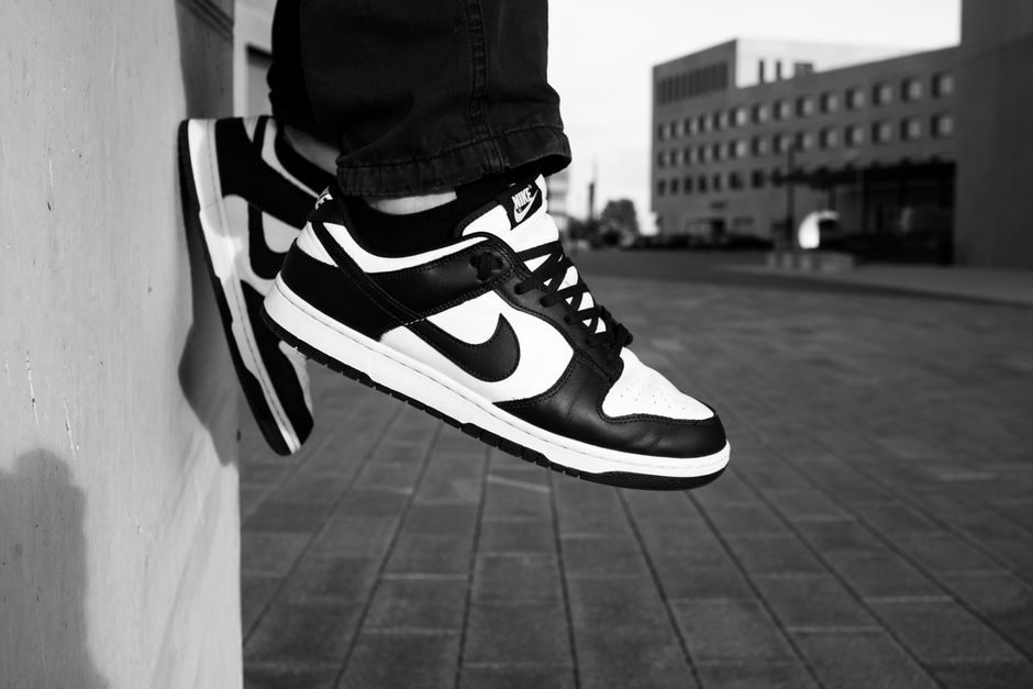 Stylish black and white sneakers resting against an urban wall in a grayscale setting.
