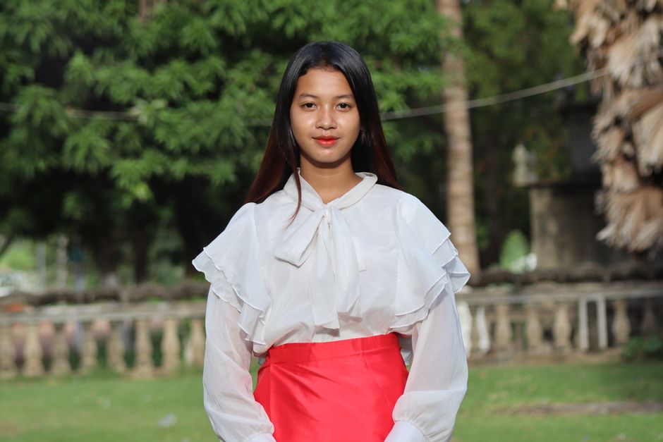 Young Cambodian woman in traditional attire posing outdoors during the day.