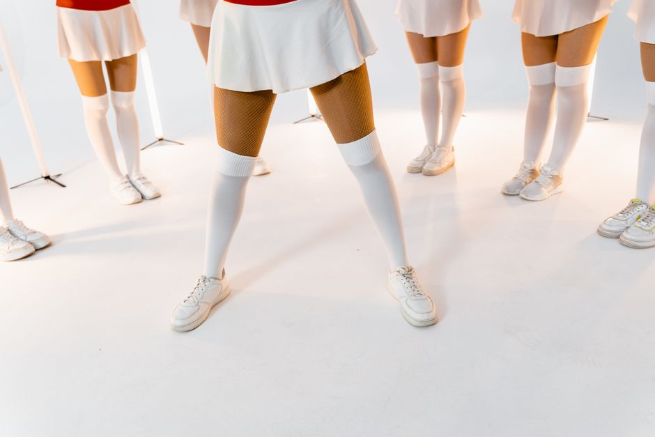 Cheerleading group in uniform displaying coordinated white skirts and sneakers.
