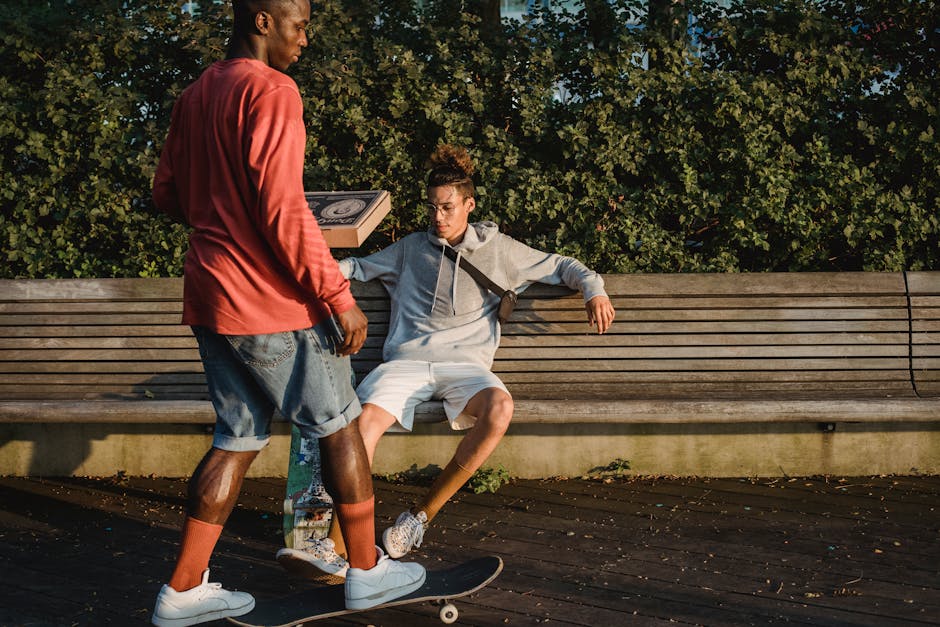 Serious diverse male skaters in casual wear chilling in park before eating pizza