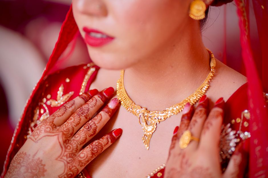 Elegant close-up of a bride showcasing intricate henna and gold jewelry, evoking cultural beauty.