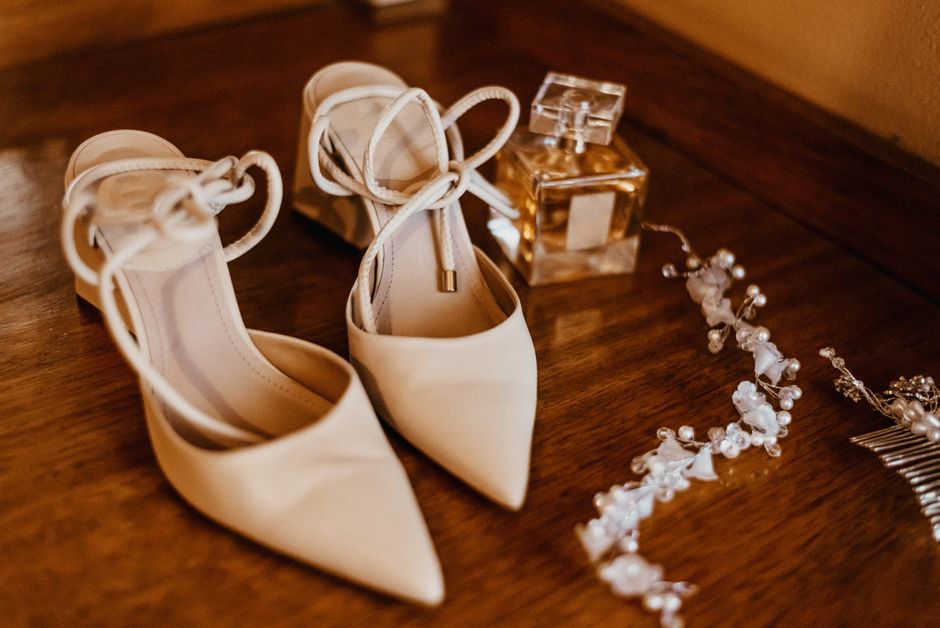 A beautiful display of ivory bridal shoes, a crystal perfume bottle, and a delicate hair accessory.