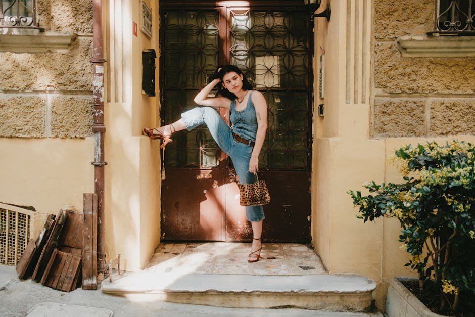 Stylish woman in denim poses confidently at a vintage doorway outdoors.