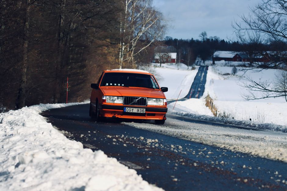 Orange Volvo car navigating a snow-covered road in Jönköping, Sweden during winter.