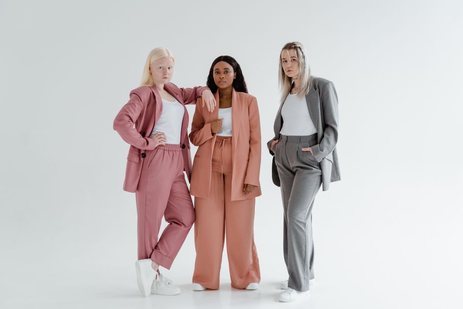 Three diverse women in stylish suits standing confidently in a studio.